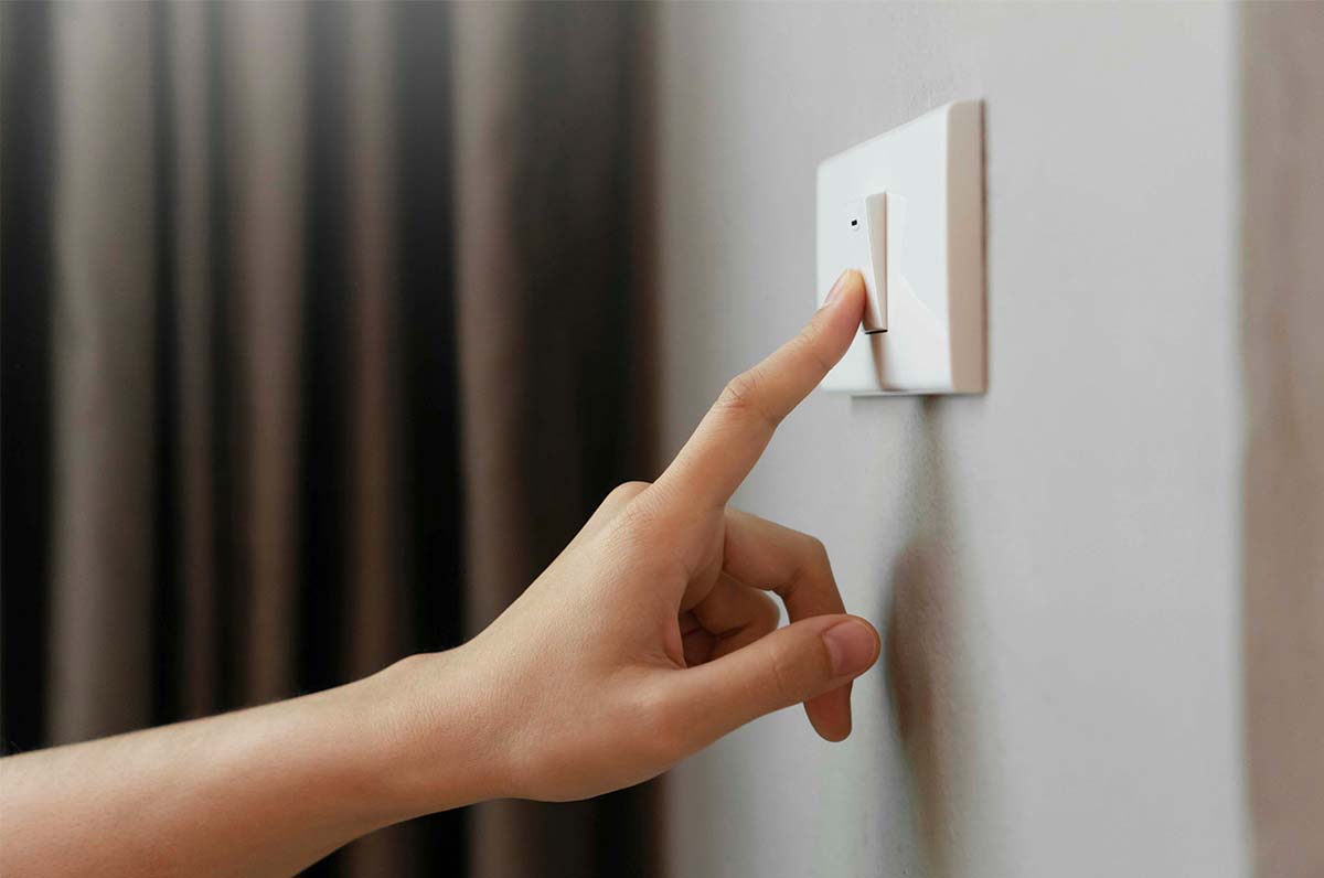 Pessoa a carregar em interruptor elétrico